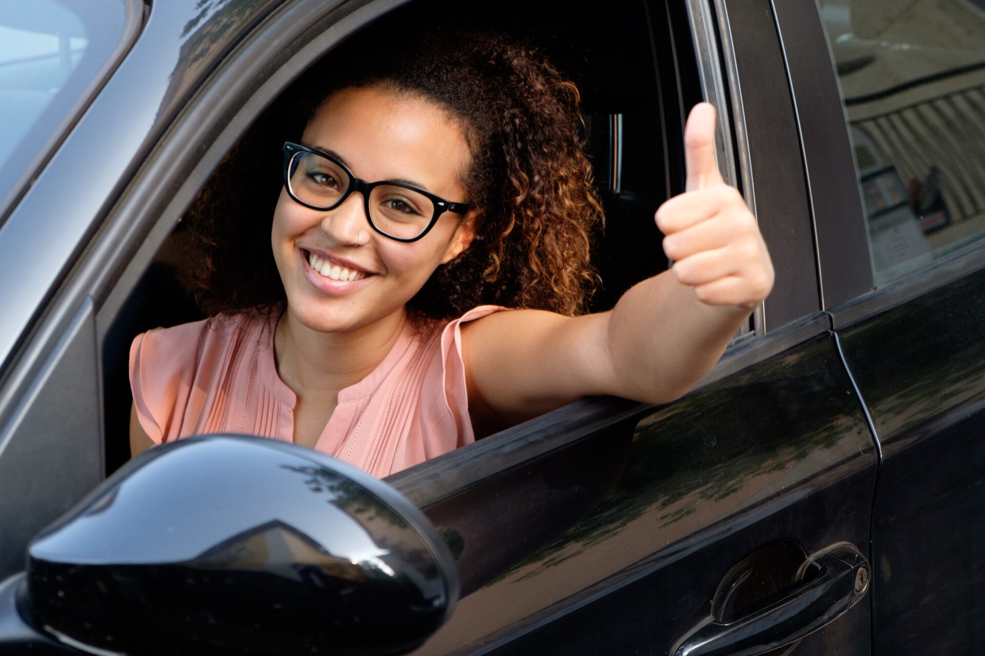 Happy young woman seated in her car Standard Insurance